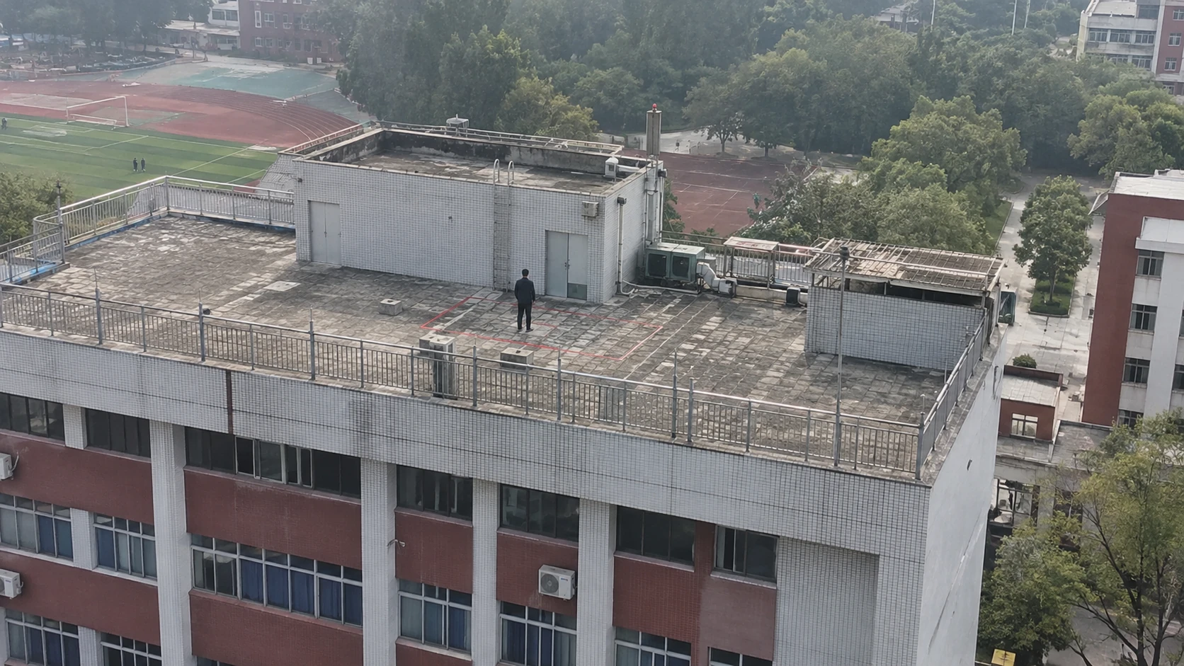 校园屋顶危险区域进入巡查：独立无人机航拍场景与红色目标标注示意